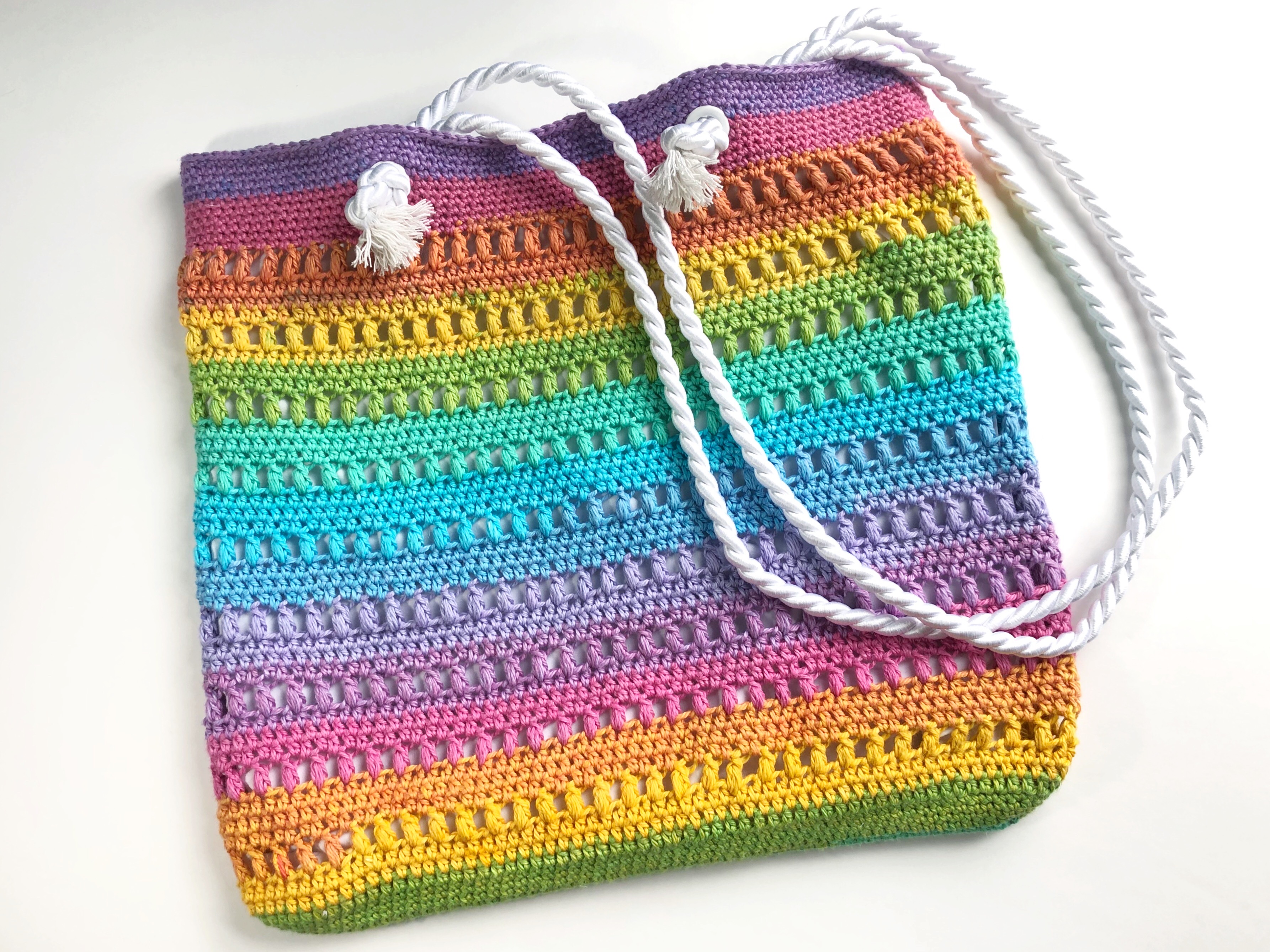 Crochet tote bag made with rainbow colored cotton yarn.