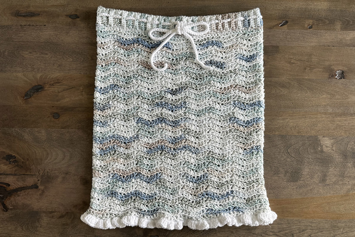 A ripple pattern crocheted pencil skirt in ocean colors displayed on a wood background.